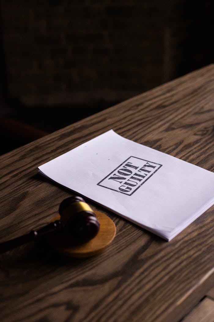 Home A legal gavel next to a Not Guilty document on a wooden table, symbolizing justice.